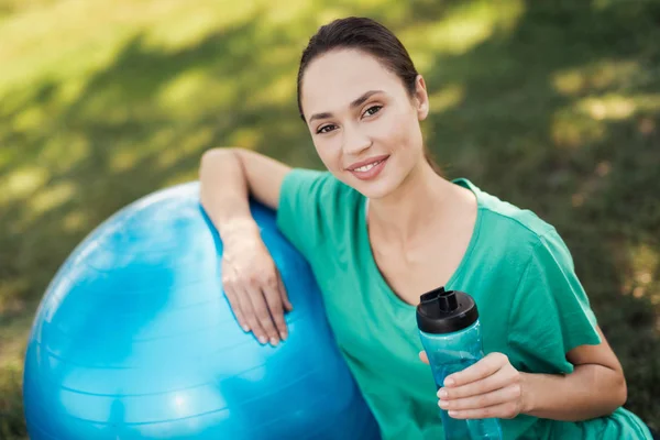 Yoga del embarazo. Mujer embarazada en una camiseta verde está sentada junto a la bola azul para el yoga — Foto de Stock