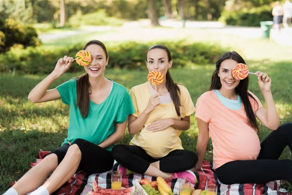 Tre gravida kvinnor poserar i en picknick park med stora färgade godis — Stockfoto