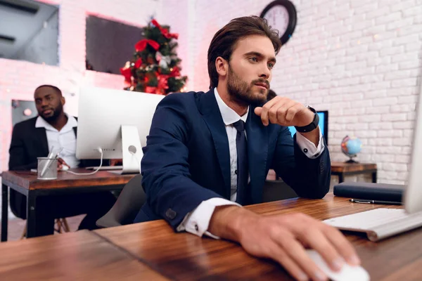 Les gens travaillent à la veille de la nouvelle année. Au premier plan se trouve un homme assis sur son lieu de travail et qui travaille. . — Photo