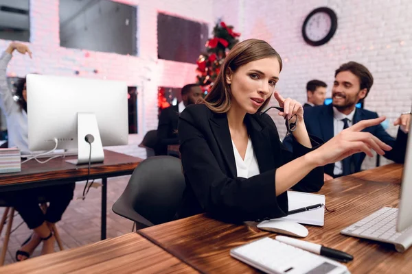 People work on the eve of the new year. In the foreground the woman who sits at her workplace poses.