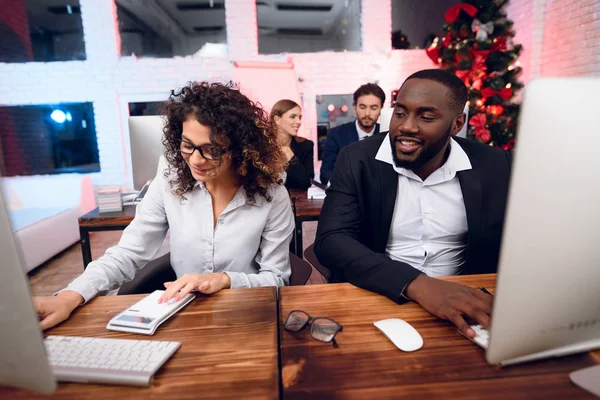 Um homem e uma mulher estão a trabalhar na véspera do Ano Novo. Eles estão posando em seus locais de trabalho e estão ocupados com o trabalho . — Fotografia de Stock