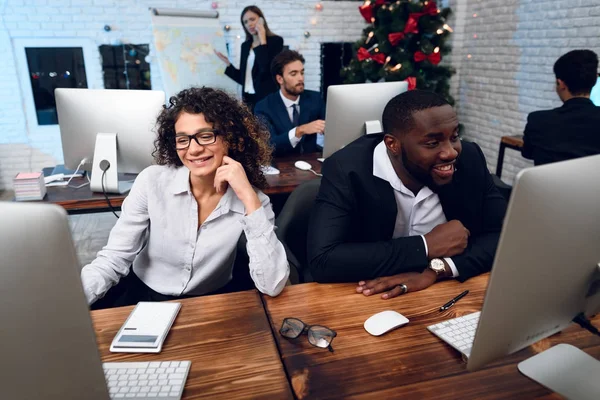 A man and a woman are working on the eve of the new year. They are posing in their workplaces and are busy with work.