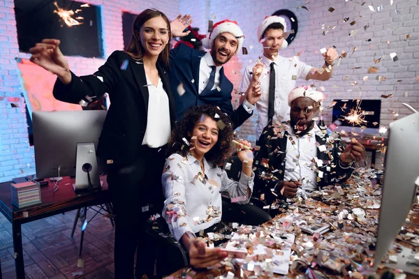 La gente trabaja en la oficina en el año nuevo. Se están preparando para cumplir el nuevo año en la oficina. Cerca de moscas confetti . — Foto de Stock