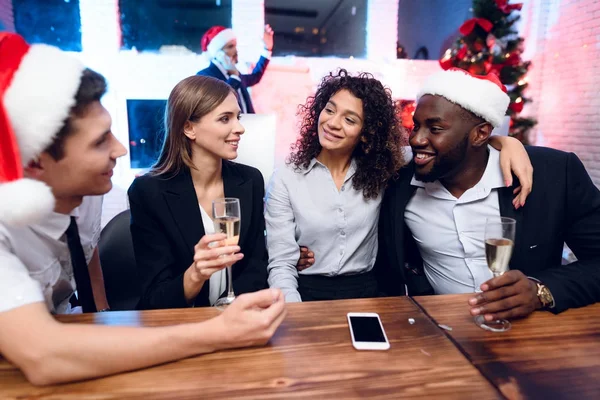 As pessoas estão se preparando para conhecer o novo ano no escritório. Sentam-se com copos de champanhe nas mãos e divertem-se. — Fotografia de Stock