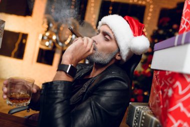 Bir siyah deri ceket şık Noel Baba'ya bir puro sigara ve viski içiyor. Yeni yıl hediyeleri ile çevrili oturuyor.
