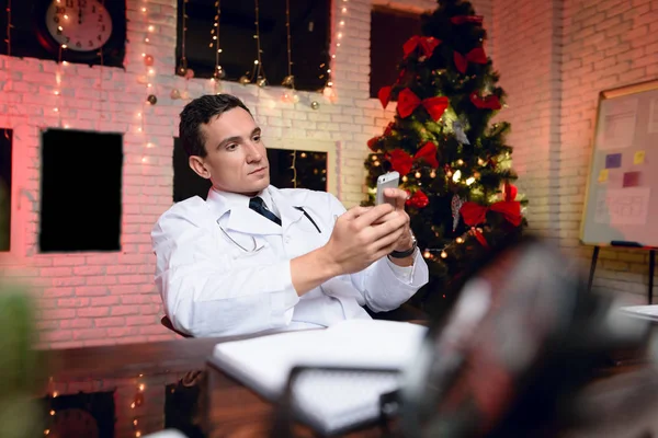 Läkaren arbetar på nyårsafton. Han talar i telefon. — Stockfoto