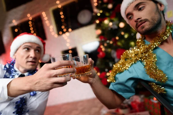 Due medici celebrano il nuovo anno in ufficio. Sbattono i bicchieri con il whisky . — Foto Stock