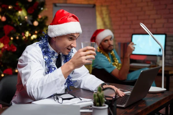 Il dottore lavora la vigilia di Capodanno. Si mise il cappello di Capodanno e regge un bicchiere di whisky. . — Foto Stock