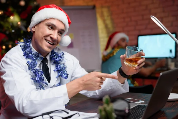 El doctor trabaja en Nochevieja. Se puso su gorra de Año Nuevo y tiene un vaso de whisky. . —  Fotos de Stock