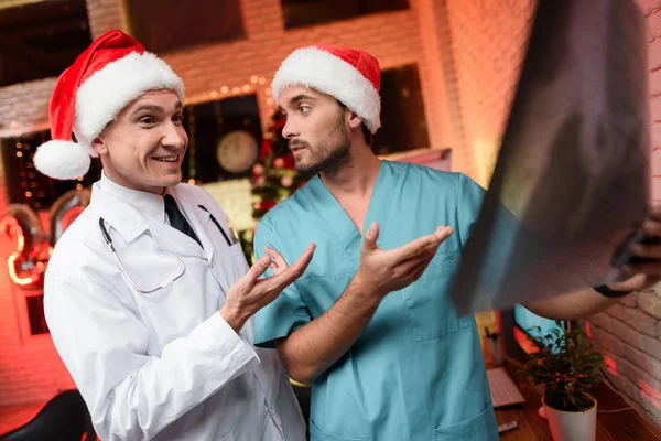 Due medici lavorano a Capodanno e discutono una radiografia che si tiene in mano . — Foto Stock