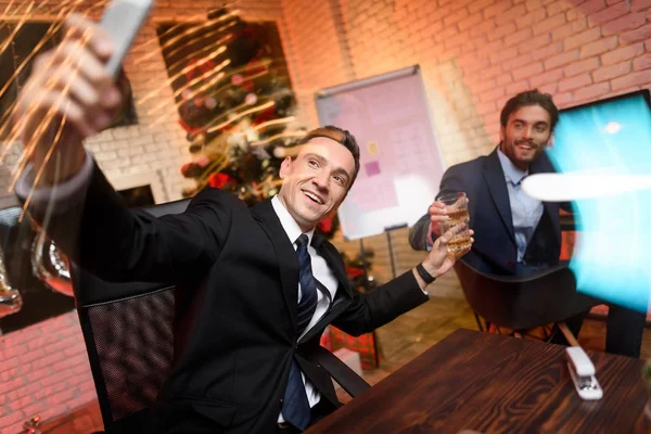 Ofiste oturan ve New Year's Eve üzerinde çalışan iş adamı. O bir selfie yanına oturur onun yüzüğünü ile yapar. — Stok fotoğraf