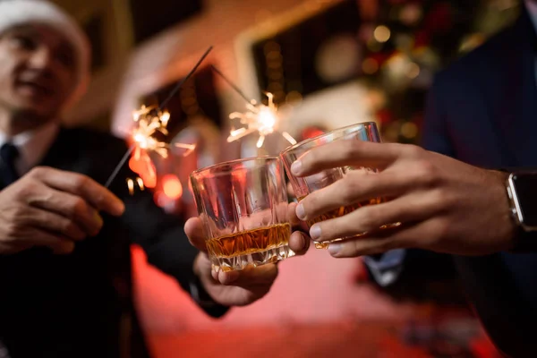 Un uomo d'affari e il suo collega festeggiano un nuovo anno in ufficio. Sbattono i bicchieri con il whisky . — Foto Stock