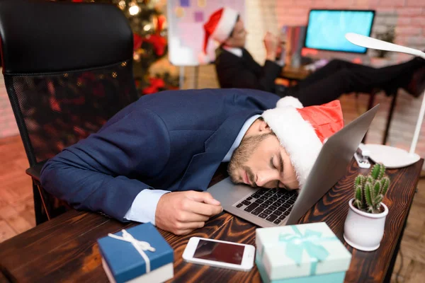 Üzletember dolgozik a New Year's Eve. Ő már nagyon fáradt volt, és elaludt mögött a laptop. — Stock Fotó