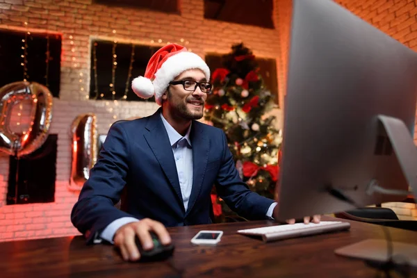 Empresário na véspera de Ano Novo no escritório. Ele joga no computador. . — Fotografia de Stock