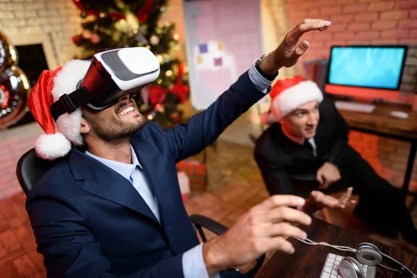 Businessman on New Year\'s Eve in the office. It has a virtual reality helmet. He plays the game.