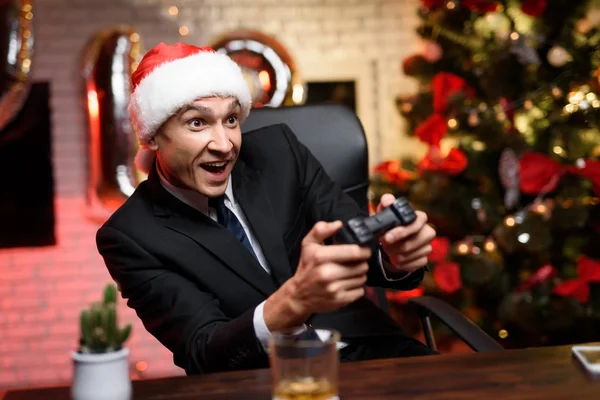 Uomo d'affari in ufficio la vigilia di Capodanno. È appassionato della console di gioco e ha un gamepad nelle sue mani . — Foto Stock