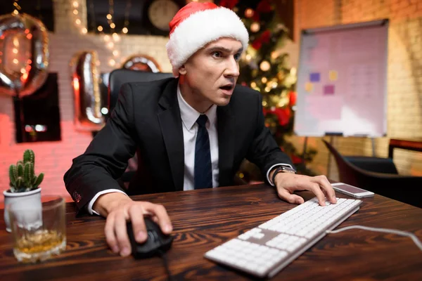 Empresário no escritório na véspera de Ano Novo. Ele joga entusiasticamente no computador . — Fotografia de Stock