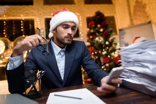 Uomo d'affari in ufficio la vigilia di Capodanno. Intorno a lui un mucchio di forme e rapporti diversi . — Foto Stock