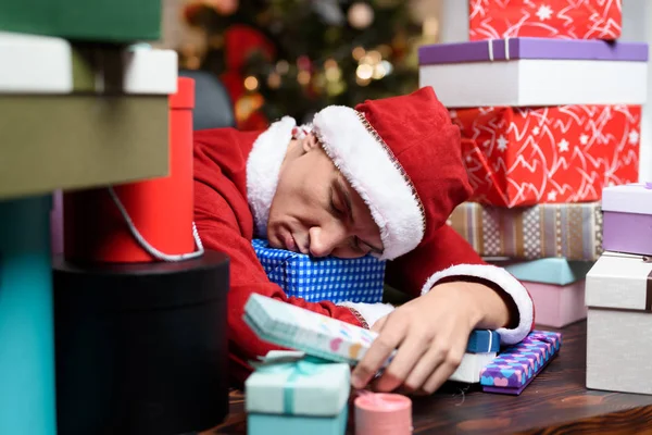 Un uomo in costume da Babbo Natale si addormentò circondato da un mucchio di regali in scatole . — Foto Stock