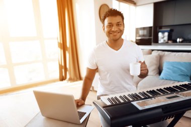 Siyah bir adam dairesinde oturma odasında oturur ve bir synthesizer çalış. O müzik oluşturur ve kahve içer.