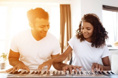 Siyah bir adam dairesinde oturma odasında oturur ve bir synthesizer çalış. Bir kız onun yanında oturuyor.