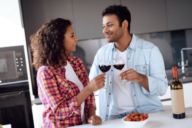 Siyah erkek ve kadın mutfakta evde şarap içmek. Onlar şefkat ve sevgi ile birbirlerine bakıyorlar.