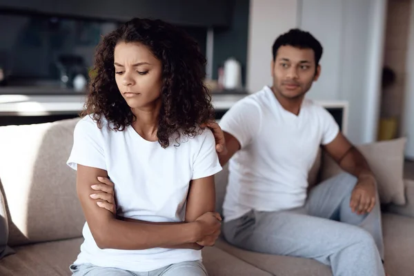 Black man and woman are sitting on the couch. The woman in offense turned away from the man. — Stock Photo, Image