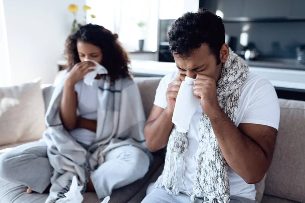 黑人男人和女人坐在沙发上。他们感冒了, 用纸巾擤鼻子。. — 图库照片
