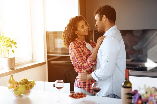 Черные мужчины и женщины на кухне дома обнимаются. Они смотрят друг на друга с нежностью и любовью. . — стоковое фото