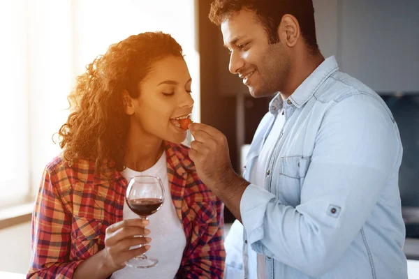 Hombres y mujeres negros en la cocina en casa beben vino. Se miran con ternura y amor . — Foto de Stock