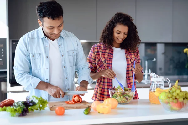 Чёрные мужчина и женщина дома на кухне. Они готовят вкусный и здоровый завтрак. Они готовят вместе. . — стоковое фото
