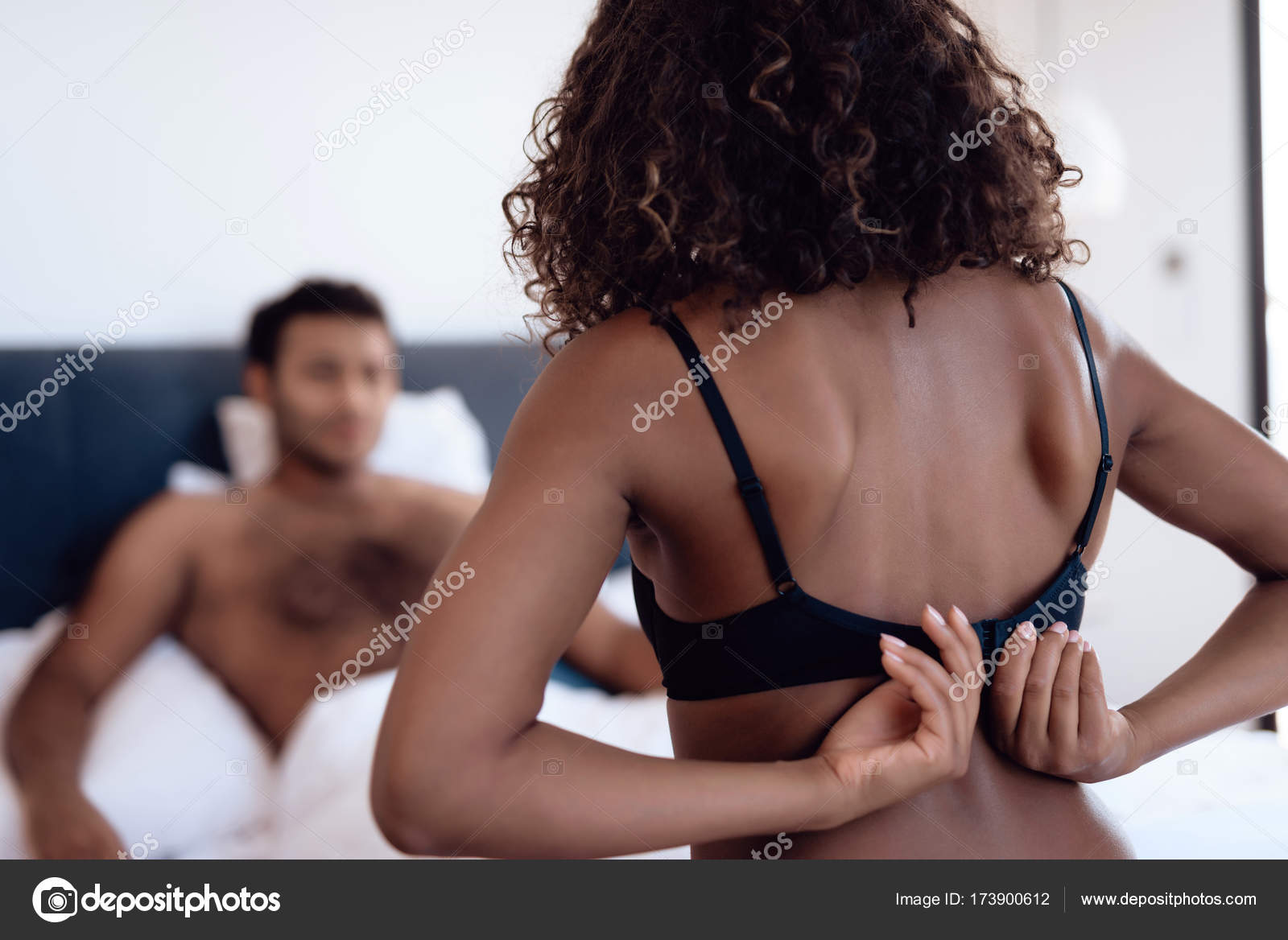 The man is lying on the bed and the woman is approaching him erotically picture