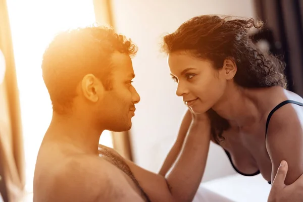 The man is lying on the bed and the woman is approaching him erotically. The woman has beautiful sexy underwear. — Stock Photo, Image