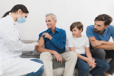 Yaşlı bir adamın bir insülin vurdu bir hemşire yapar. Bir hemşire bir maske ve eldiven kanepede oturuyor.