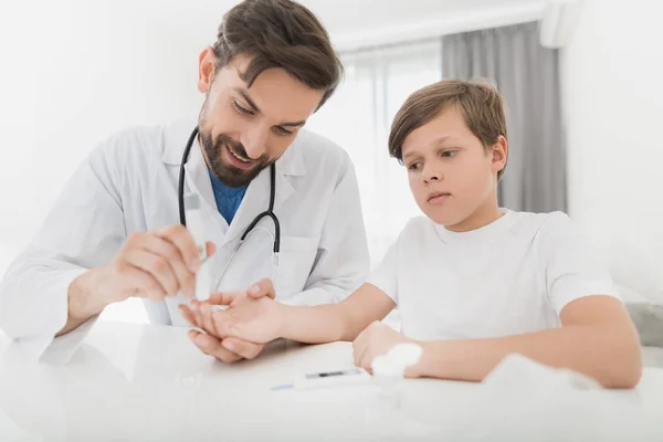 El médico toma una muestra de sangre del niño para comprobar si tiene azúcar. El chico soporta pacientemente el procedimiento. — Foto de Stock