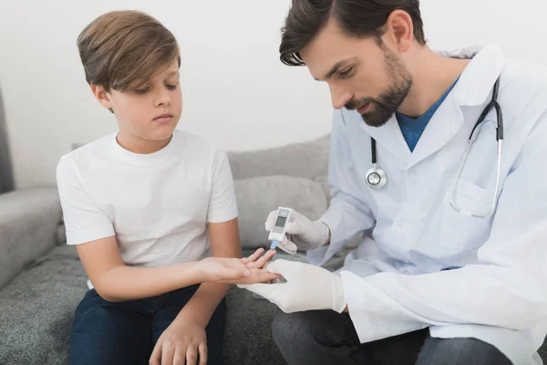 医生用白色医用手套将男孩的血液样本带到糖的水平. — 图库照片