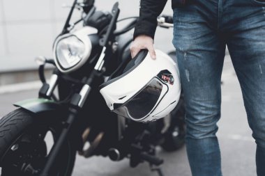 Genç bir adam bir elektrikli motosiklet duruyor.