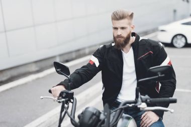 Sakallı genç bir adam onun elektrikli motosiklet üzerinde oturur.