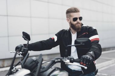 Sakallı genç bir adam onun elektrikli motosiklet üzerinde oturur.