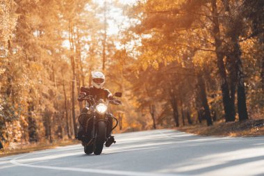 Bir kask içinde genç bir adam bir orman yolu bir elektrikli motosiklet sürme.