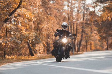 Bir kask içinde genç bir adam bir orman yolu bir elektrikli motosiklet sürme.