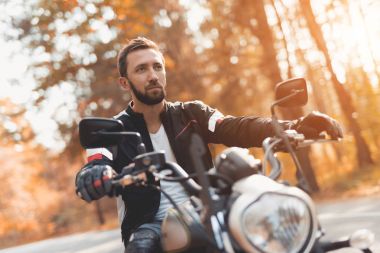 Bir sakallı bir genç adam bir orman yolu bir elektrikli motosiklet sürme.