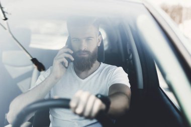 Bir sakallı bir genç adam bir elektrikli araç direksiyon başında oturur.