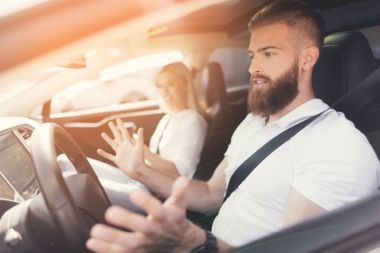 Bir sakallı bir genç adam bir elektrikli araç direksiyon başında oturur.