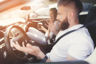 Bir sakallı bir genç adam bir elektrikli araç direksiyon başında oturur.