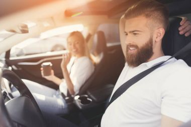 Bir sakallı bir genç adam bir elektrikli araç direksiyon başında oturur.