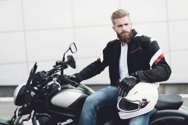 Sakallı genç bir adam onun elektrikli motosiklet üzerinde oturur.