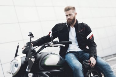 Sakallı genç bir adam onun elektrikli motosiklet üzerinde oturur.