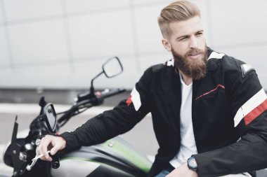 Sakallı genç bir adam onun elektrikli motosiklet üzerinde oturur.