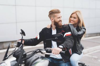 Genç bir adam ve bir modern elektrikli motosiklet üzerinde oturan kız.